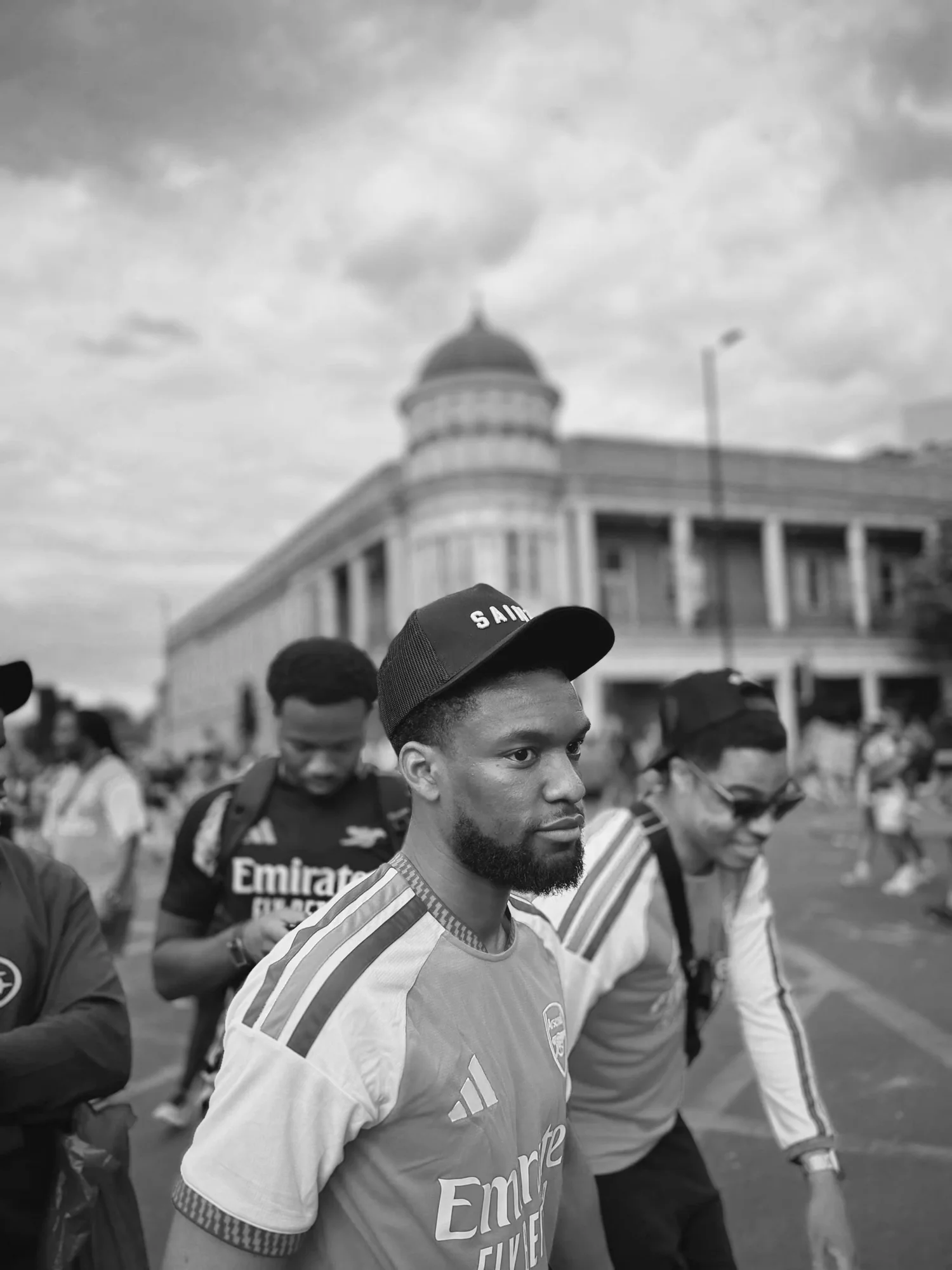 Group walking, front man wearing a SAINT cap
